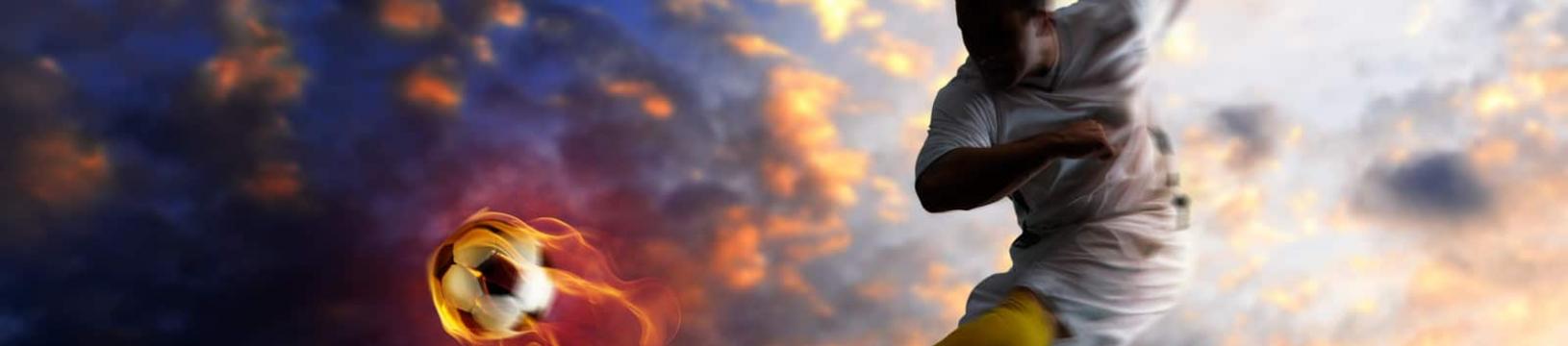 Young soccer player kicking a flaming football